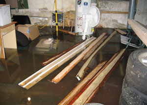 A severely flooding basement in Squamish, with lumber and personal items floating in a foot of water