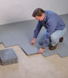 Contractors installing basement subfloor tiles and matting on a concrete basement floor in Langford, British Columbia
