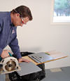 installing a waterproof vapor barrier on a basement floor to prepare for basement carpeting in a Duncan home